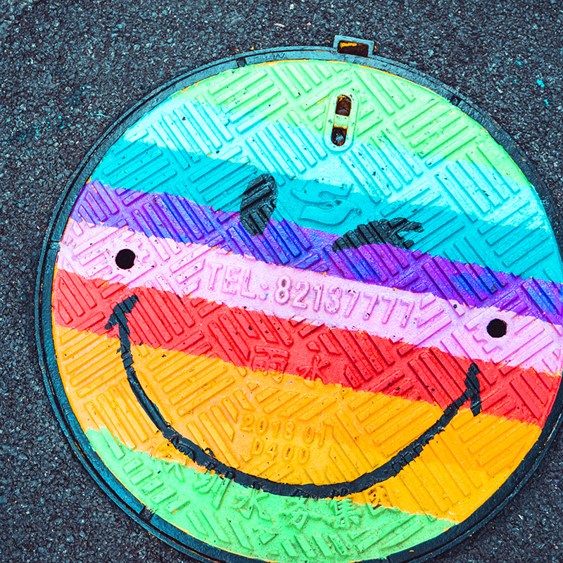 Rainbow Happy Face Painted On A Manhole Cover