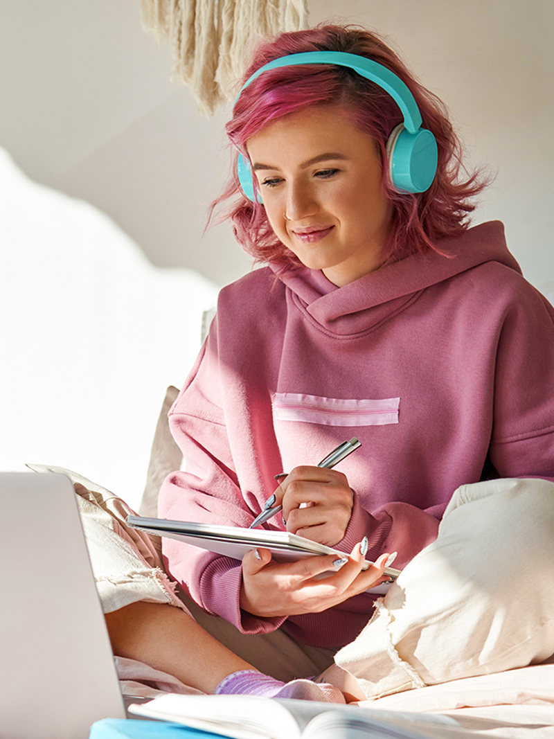 Pink Haired College Girl Studying, Wearing Headphones, Surrounded By Books